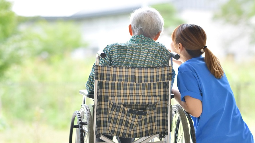 Senior im Ruhlstuhl schaut zusammen mit seiner Pflegerin auf einen See Senior im Ruhlstuhl schaut zusammen mit seiner Pflegerin auf einen See